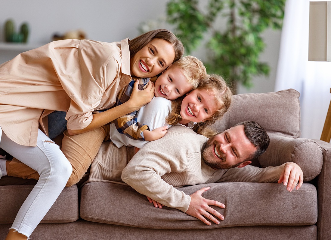 Personal Insurance - Portrait of a Cheerful Family with a Son and Daughter Having Fun Spending Time Together Playing on the Sofa at Home